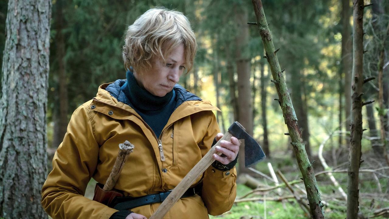 Susanne Bonard mit einer Axt in der Hand beim Überlebenstraining im Wald.