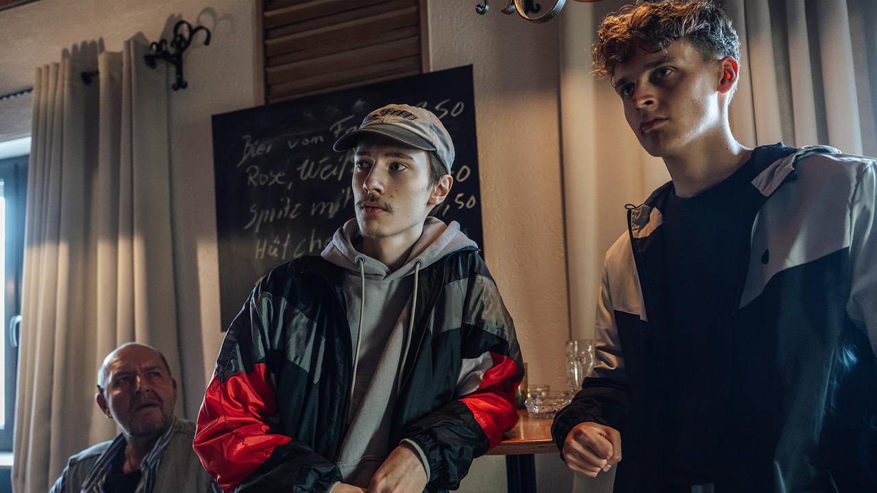 In der einzigen Kneipe von Hohenweiler sitzen alle nach Lagern getrennt: Peter Feidt und Nils Feidt lehnen an einem Stehtisch.