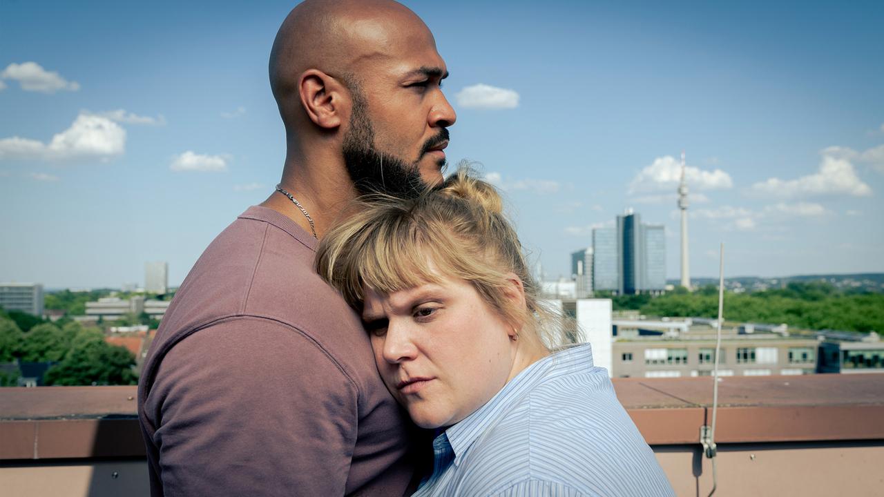 Rosa Herzog steht gemeinsam mit Otto Pösken auf dem Dach und lehnt ihren Kopf an seine Brust.
