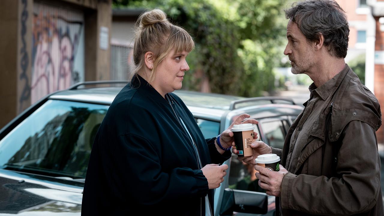 Peter Faber erwartet Rosa Herzog mit einem Kaffee auf der Straße vor ihrer Wohnung.