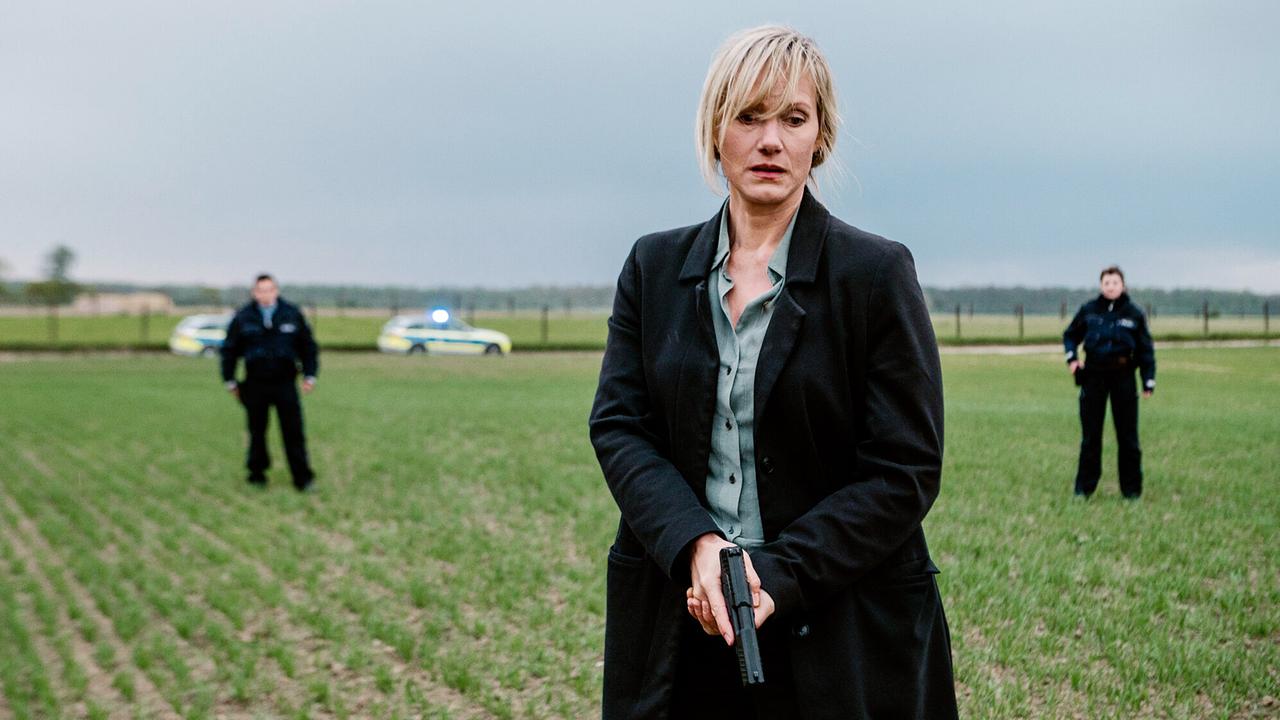 "Tatort: Gier und Angst": Kommissarin Martina Bönisch (Anna Schudt) mit Streifenbeamten bei einer Verfolgung auf einem Feld.