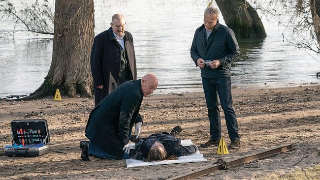 "Tatort: Hubertys Rache": Max Ballauf (Klaus J. Behrendt, r) und Freddy Schenk (Dietmar Bär, l) sind am frühen Morgen am Rheinufer im Einsatz. Rechtsmediziner Dr. Roth (Joe Bausch, kniend) untersucht die Leiche eines Mannes, die hier gefunden wurde.