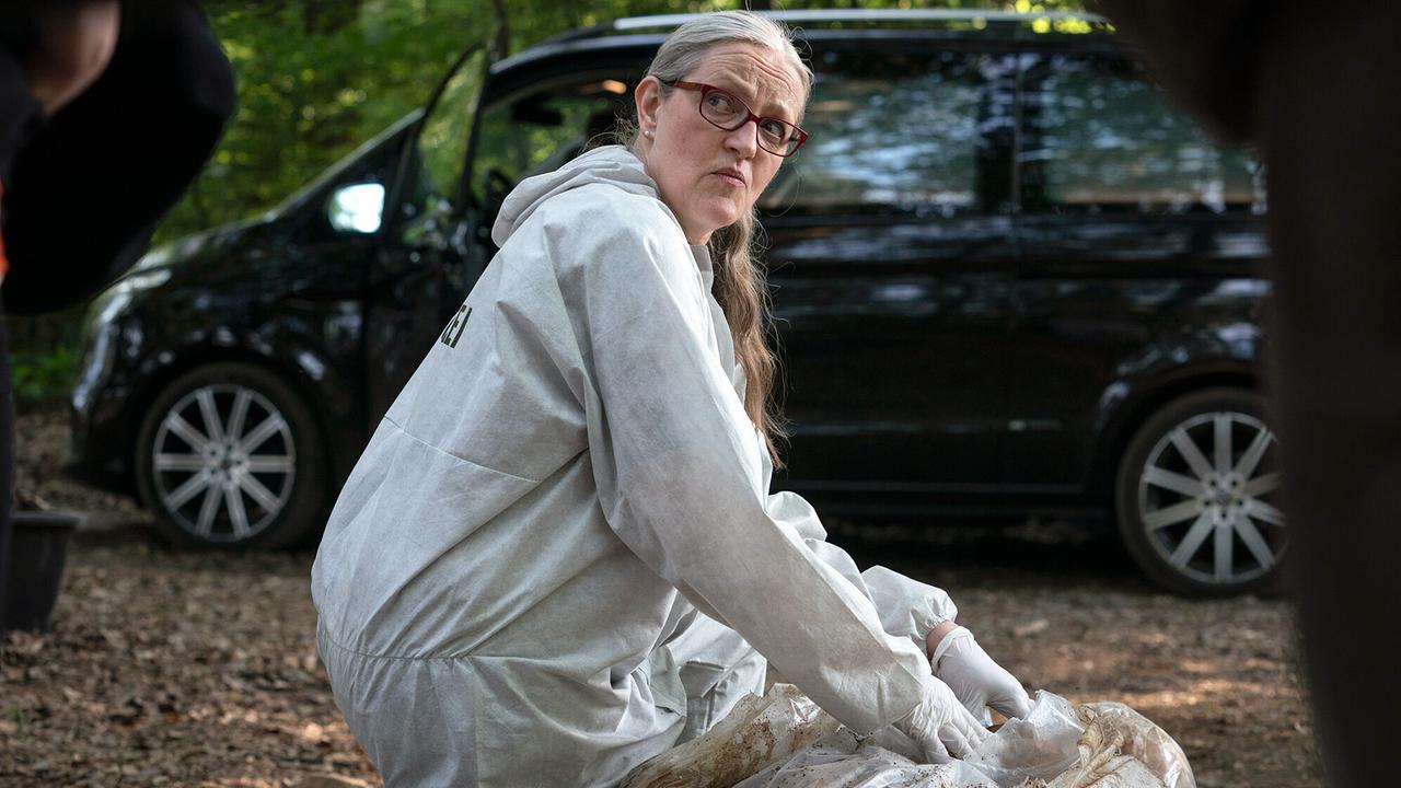 "Tatort: Liebe mich!": Rechtsmedizinerin Dr. Greta Leitner (Sybille Schedwill) öffnet die Kunststoffplane, in die eine Leiche gewickelt wurde. In einem Bestattungswald wurde sie entdeckt, bei Vorbereitungen für ein Urnenbegräbnis.