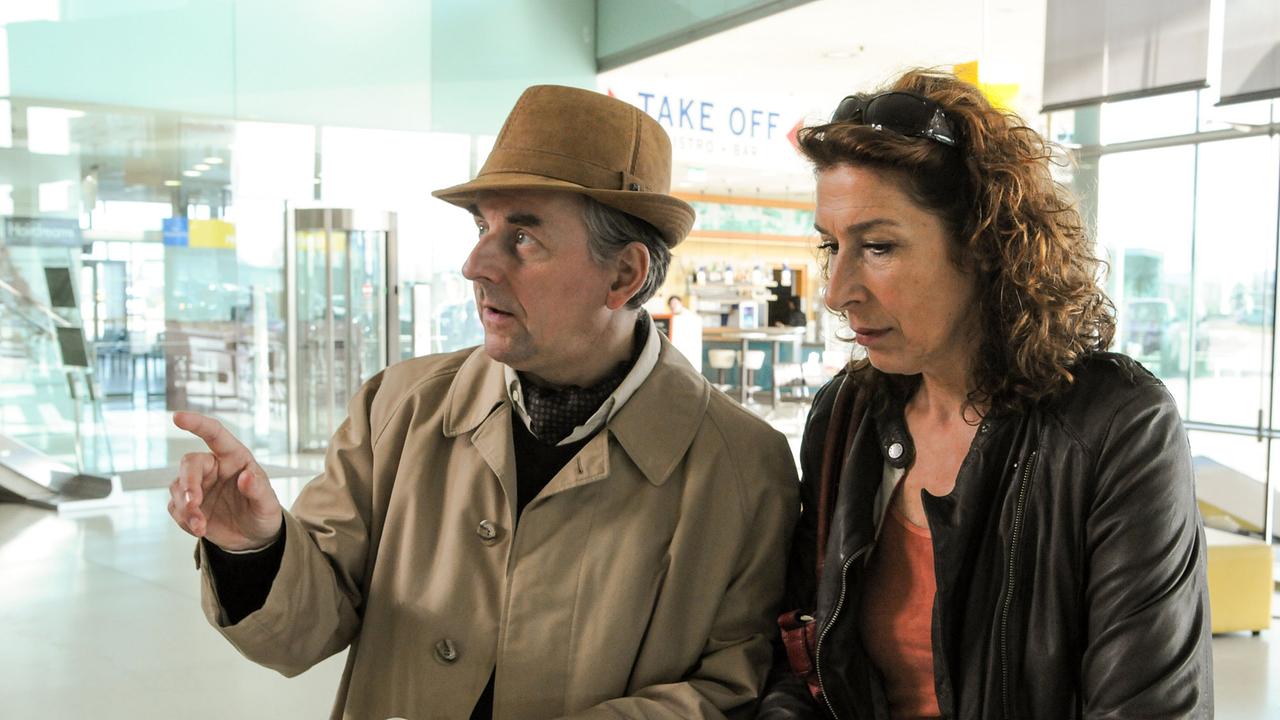 "Tatort - Paradies": Bibi (Adele Neuhauser) erkundigt sich bei einem Rentner (Johannes Silberschneider) am Flughafen Graz nach ihrem Flug nach Kreta.