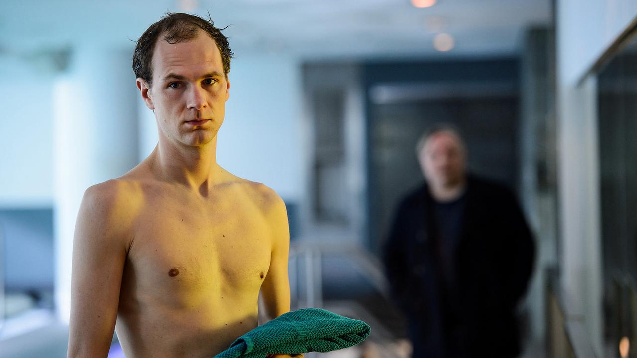 "Tatort: Schwanensee": Andreas Kullmann (Robert Gwisdek, l.) geht jeden Morgen im Schwimmbad des Therapiezentrums „Haus Schwanensee“ schwimmen. Frank Thiel (Axel Prahl, r.) beobachtet ihn.