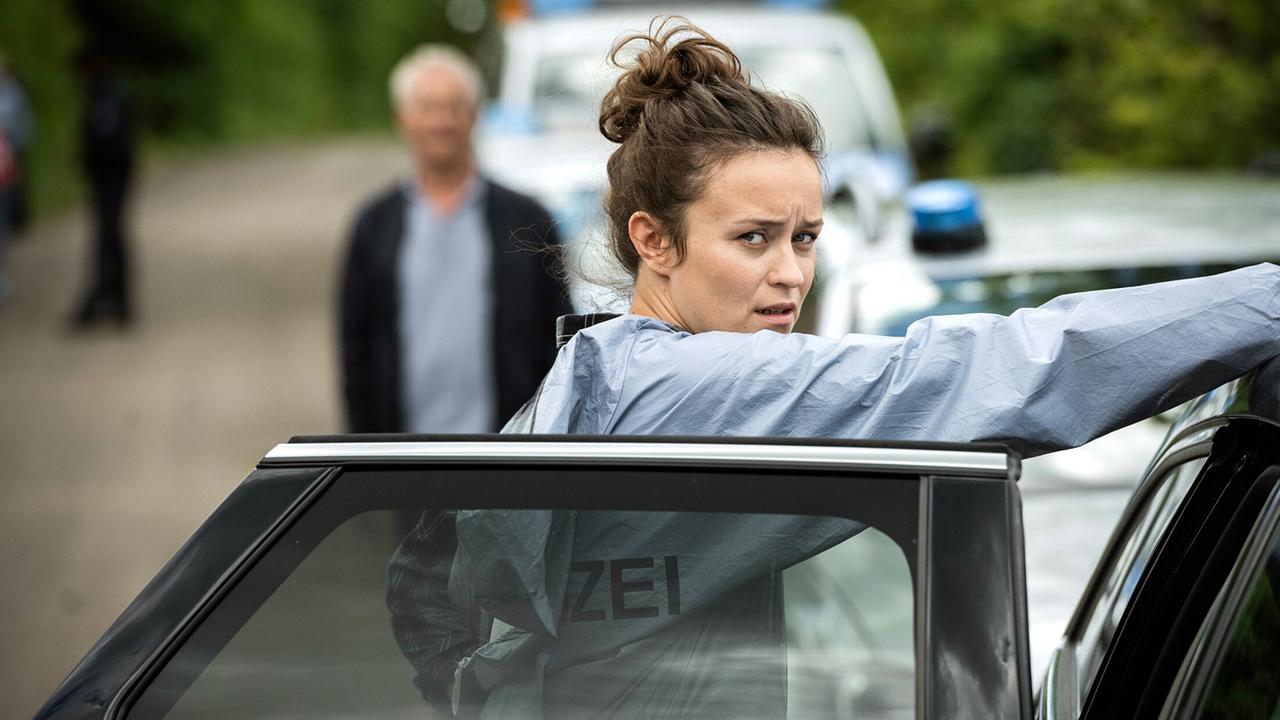 "Tatort: Spur des Blutes": Natalie Förster (Tinka Fürst) legt ihre Schutzkleidung an, im Hintergrund: Kommissar Max Ballauf (Klaus J. Behrendt)