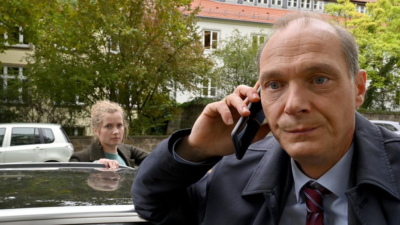 "Tatort: Unsichtbar": Peter Michael Schnabel (Martin Brambach) telefoniert an seinen Dienstwagen gelehnt, auf der anderen Seite Leo Winkler (Cornelia Gröschel).