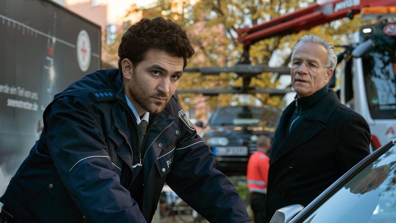 "Tatort: Vier Jahre": Polizist Emre Topal (David Vormweg) und sein Kollege versuchten für Ruhe zu sorgen auf der Silvesterparty vor vier Jahren. Dass Kommissar Max Ballauf (Klaus J. Behrendt, r) ihn jetzt ausgerechnet zu diesem Einsatz nochmal befragt, kommt überraschend. Aber er versucht sich zu erinnern – so gut es eben geht nach all der Zeit.