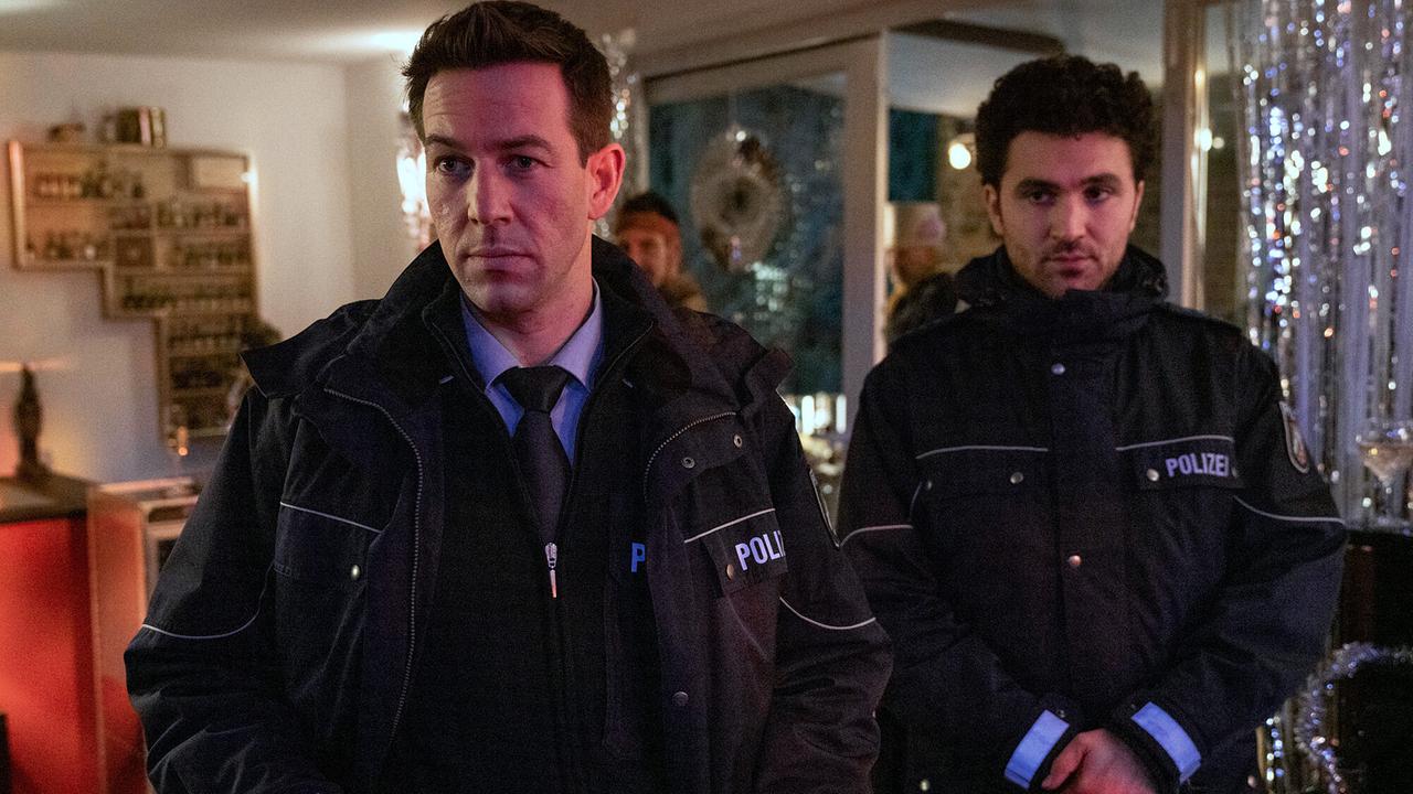 "Tatort: Vier Jahre": In der Silvesternacht sollen sie für Ruhe sorgen: Nach einer Beschwerde aus der Nachbarschaft bitten Polizist Frank Heise (Florian Anderer) und sein Kollege Emre Topal (David Vormweg, r.) bei der Party im Hause Seitz um etwas Rücksicht auf die Nachbarn.