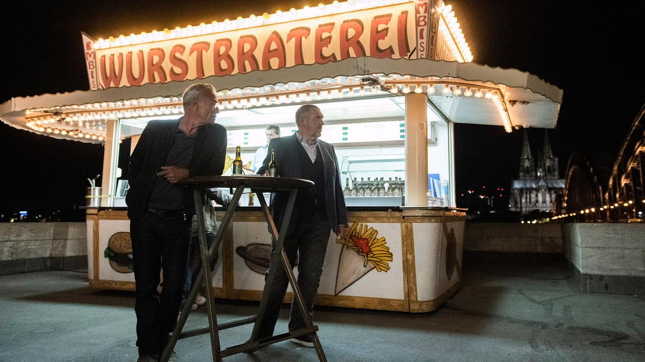 "Tatort: Wie alle anderen auch": Feierabend an der Wurstbraterei: Freddy Schenk (Dietmar Bär, rechts) und Max Ballauf (Klaus J. Behrendt, links) mit dem Dom und der Deutzer Brücke.