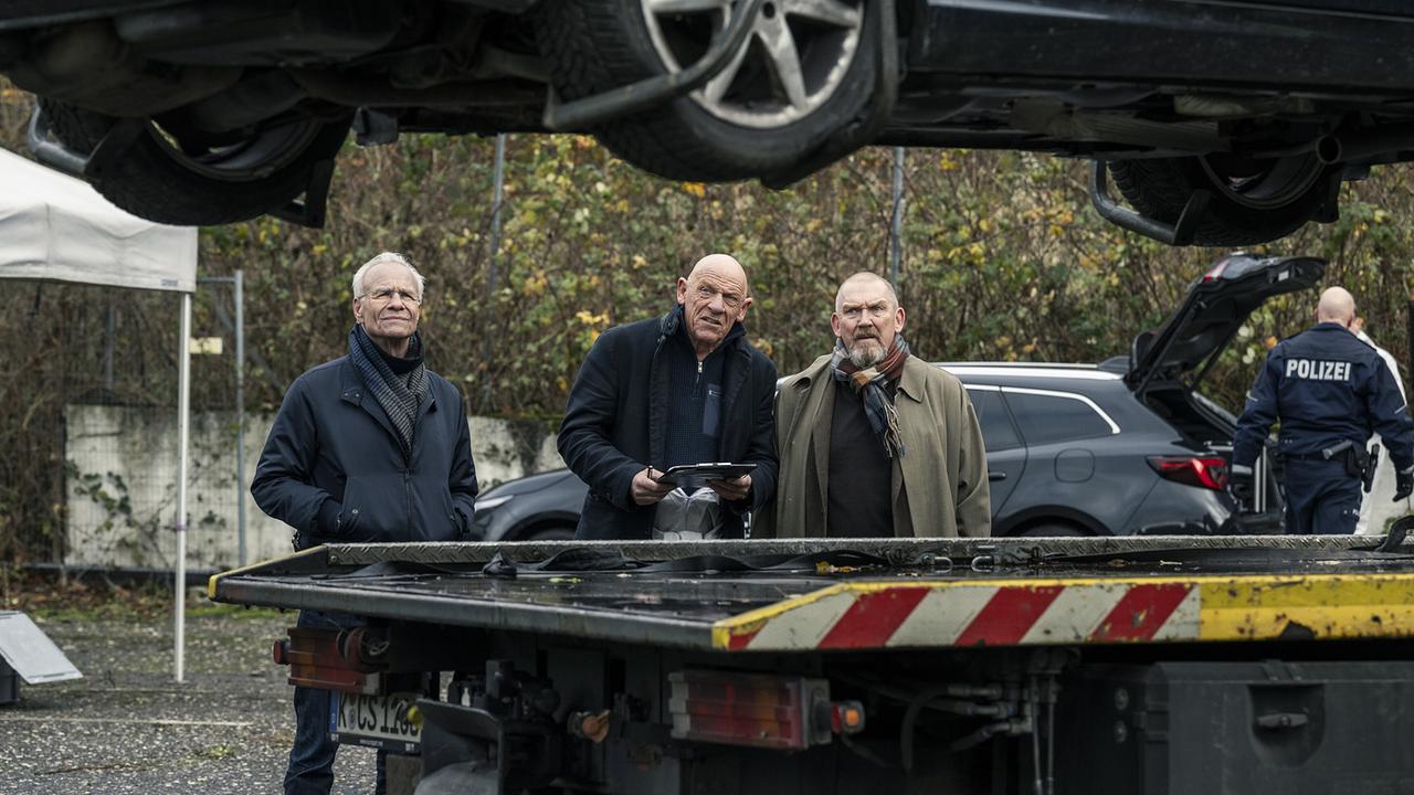 Die Kommissare Max Ballauf und Freddy Schenk zusammen mit dem Rechtsmediziner Dr. Roth am Tatort: Im Kofferraum eines ausgebrannten Autos wurde eine verkohlte Männerleiche gefunden.