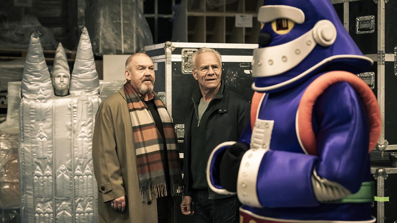 Willkommen in einer anderen Welt. Freddy Schenk und Max Ballauf suchen auf dem Studiogelände nach dem Set der Kindershow "Sachen und Lachen" und stoßen auf allerlei buntes Volk...