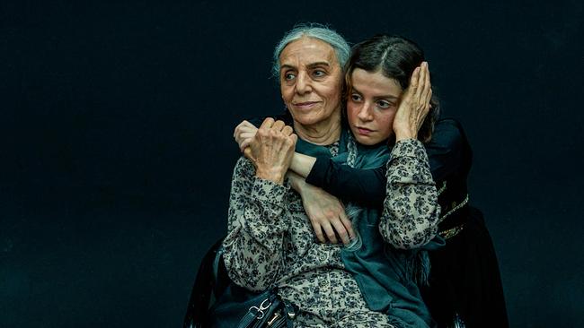 © ORF/ArtHood Films/Golden Girls Film Die junge Ghazal umarmt die ältere Tarlan von hinten vor dunklem Hintergrund, während beide in die Ferne blicken.