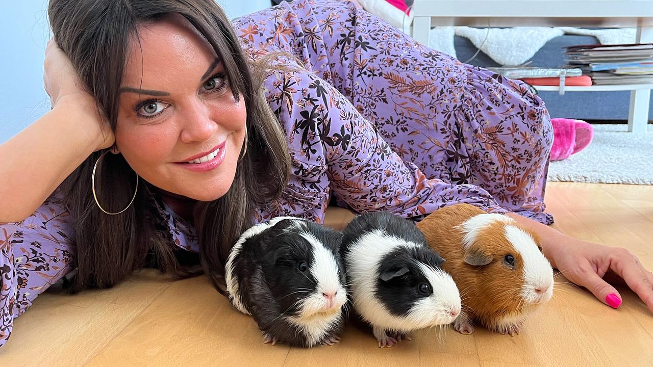 Modeexpertin Martina Reuter liegt neben ihren drei Meerschweinchen am Fußboden in einem Wohnzimmer.