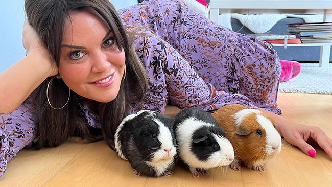 Modeexpertin Martina Reuter liegt neben ihren drei Meerschweinchen am Fußboden in einem Wohnzimmer.