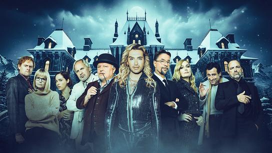 Gruppenfoto mit Max Giermann, Annette Frier, Verena Altenberger, Uwe Ochsenknecht, Axel Prahl, Bill Kaulitz, Jan Josef Liefers, Martina Hill, Serkan Kaya und Juergen Maurer vor einem großen, schneebedeckten Herrenhaus in einer winterlichen, mysteriösen Szenerie.