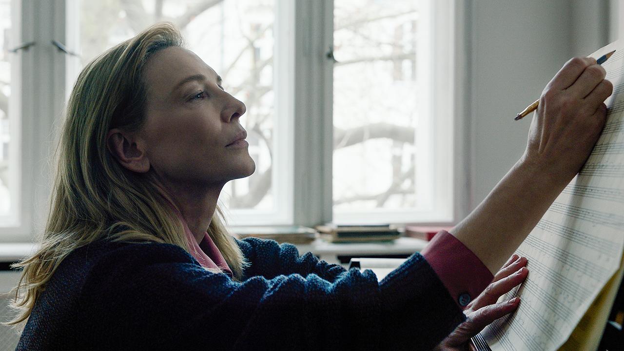 © ORF/Universal/Focus Features Cate Blanchett sitzt als Lydia Tár in einem hellen Zimmer an einem Klavier und notiert ihre Komposition mit einem Stift auf den Notenblättern