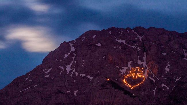 Berg mit leuchtenden Feuermotiven in Kreuz- und Herzform zur Sommersonnenwende.