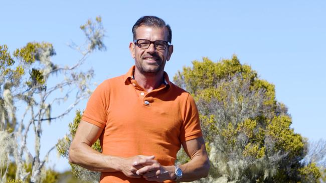 Karl Ploberger steht vor Bäumen und blauem Himmel