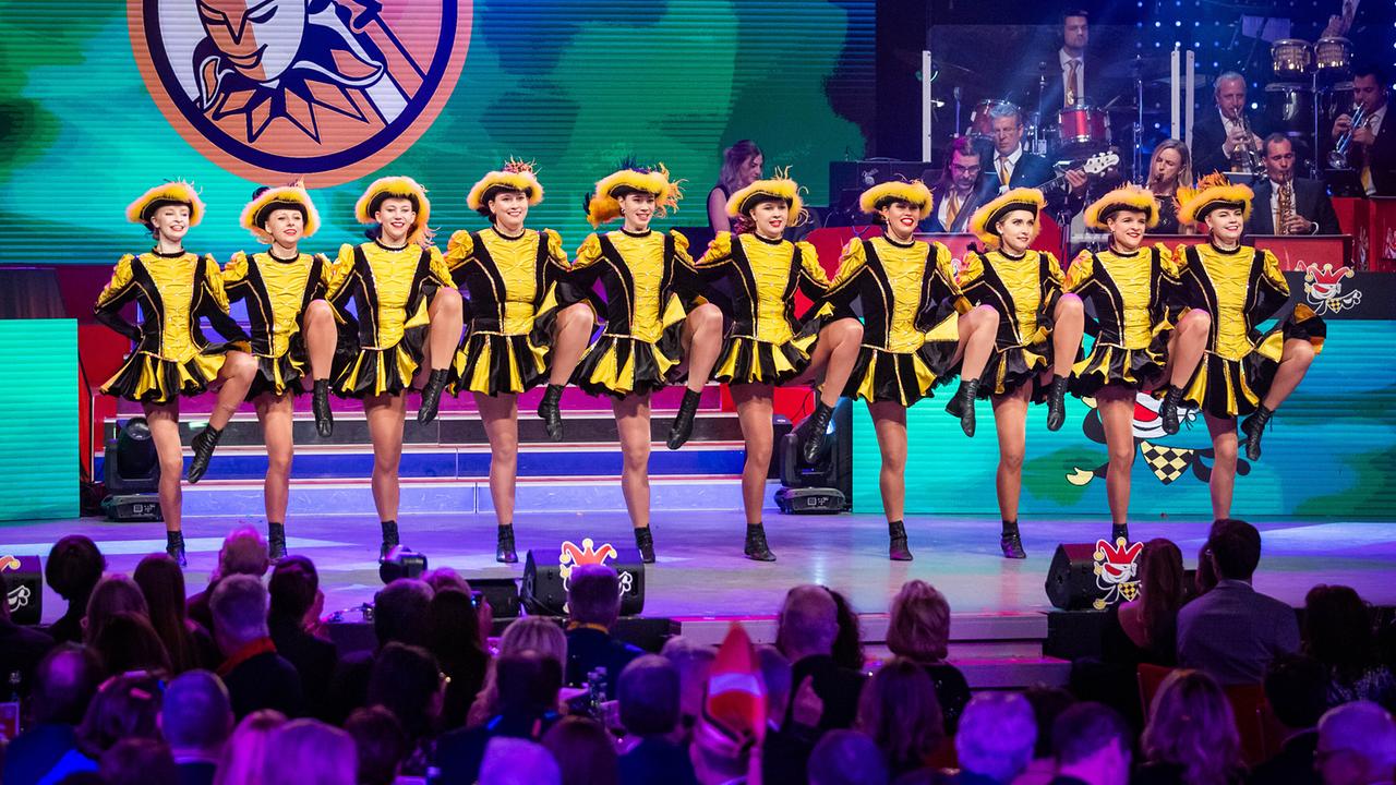 © ORF/Peter Krivograd Die "Villacher Fasching" Garde in gelb‑schwarzen Kostümen führt auf einer bunt beleuchteten Bühne vor großem Publikum eine synchronisierte Choreografie auf.