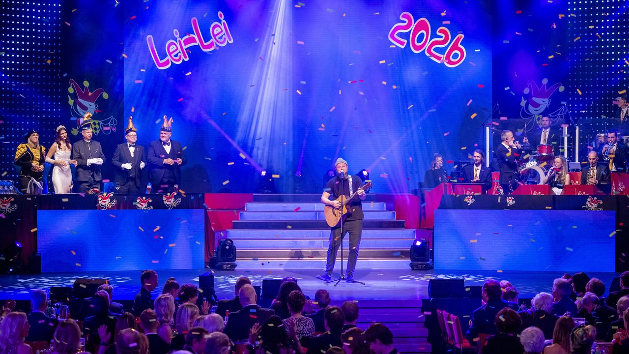 © ORF/Peter Krivograd "Beau Frost" Leonhard Beau James spielt Gitarre unter Konfettiregen auf der Villacher Bühne mit dem Schriftzug „Lei‑Lei 2026“.