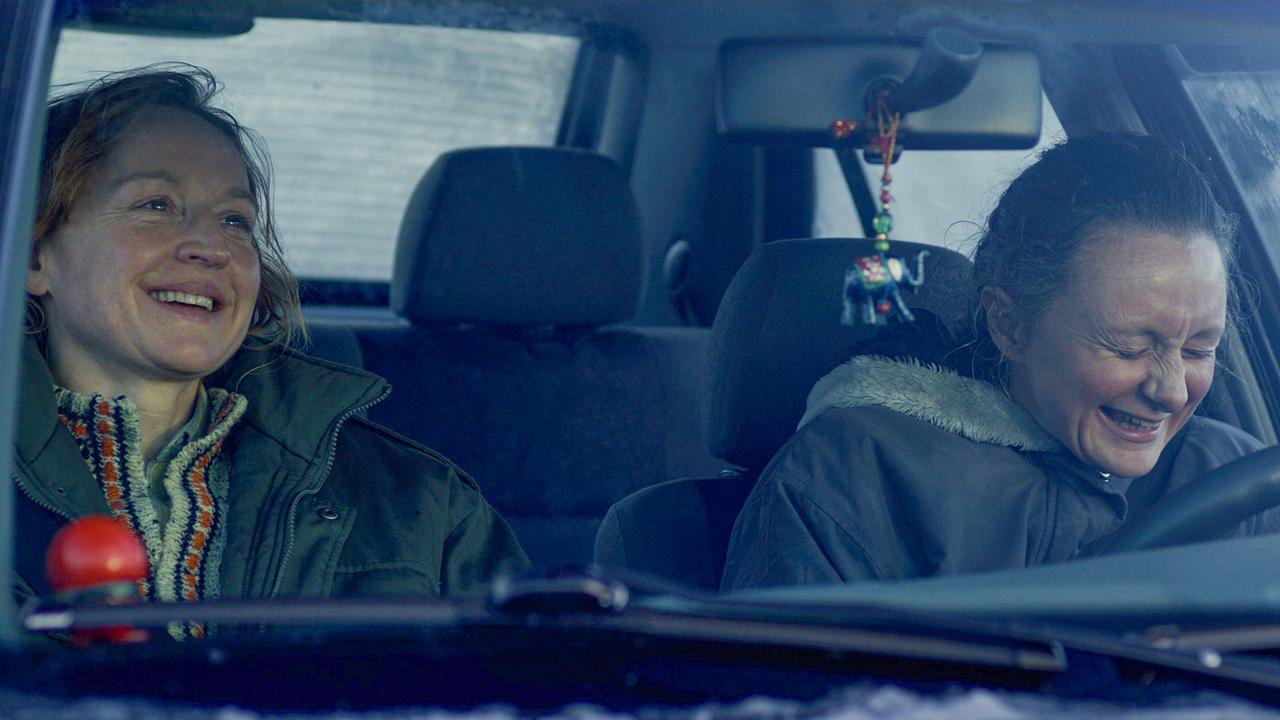 © ORF/Wega Film Marian sitzt am Beifahrersitz mit Gerti Auto. Beide lächeln.