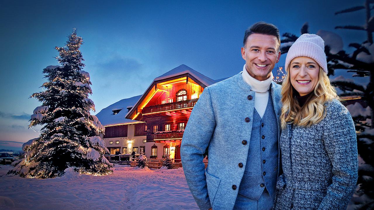© ORF/Peter Krivograd/Franz Neumayr Marco Ventre und Stefanie Hertel posieren winterlich gekleidet vor dem stimmungsvoll beleuchteten Gut Aiderbichl im Schnee.