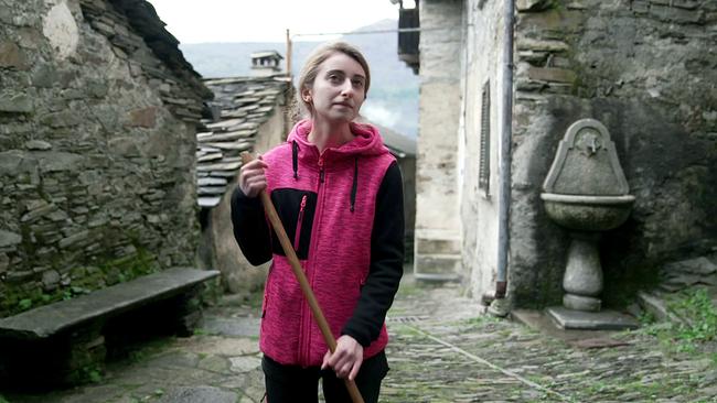 © ORF/Spiegel TV / M. Pappalardo / A. Leonardi Letizia Rubinato ist eine der Gründerinnen des Vereins zur Erhaltung des Bergdorfs. Sie steht in einer pink-schwarzen Jacke in einer engen, steingepflasterten Gasse eines alten Bergdorfes Monteviasco und hält einen Holzstock in der Hand.