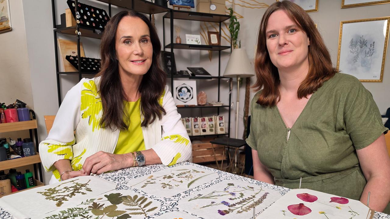 Maggie Entenfellner und Marie-Elisabeth Gantner sitzen vor Bücherregalen am Tisch mit gepressten Pflanzen und Blüten.