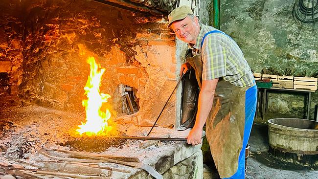Kunstschmied Klaus Kamleitner an lodernder Esse in historischer Hammerschmiede Aggsbach mit Schmiedewerkzeug.