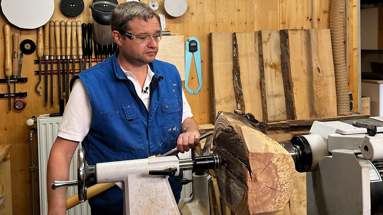 © ORF/Ab Hof TV Produktion Tischler Andreas Achleitner steht in einer Werkstatt vor einer Drechselbank und bearbeitet ein großen Holzstück.