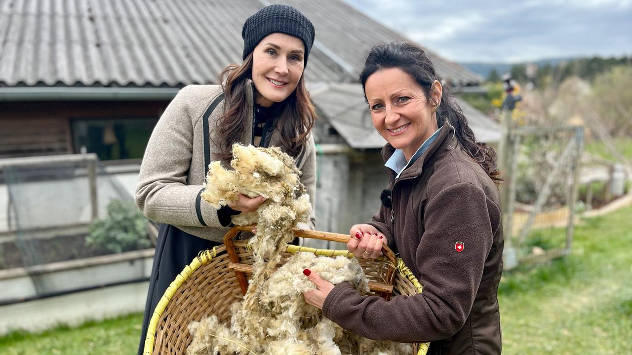 © ORF/Ab Hof TV Produktion Maggie Entenfellner und Daniela Ochabauer halten gemeinsam einen großen Korb mit frisch geschorener Schafwolle.
