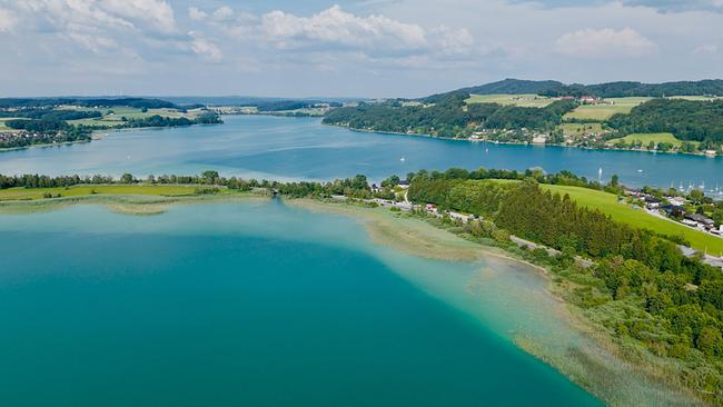 © ORF/Ab Hof TV Produktion Luftaufnahme des Trumer Seenlands: Mehrere Seen, grüne Ufer und sanfte Hügel unter blauem Himmel.