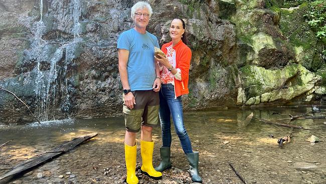 © ORF/Ab Hof TV Produktion Maggie Entenfellner und Paul Herbst stehen im Bach vor einem Wasserfall und halten einen Kalkstein in Händen.