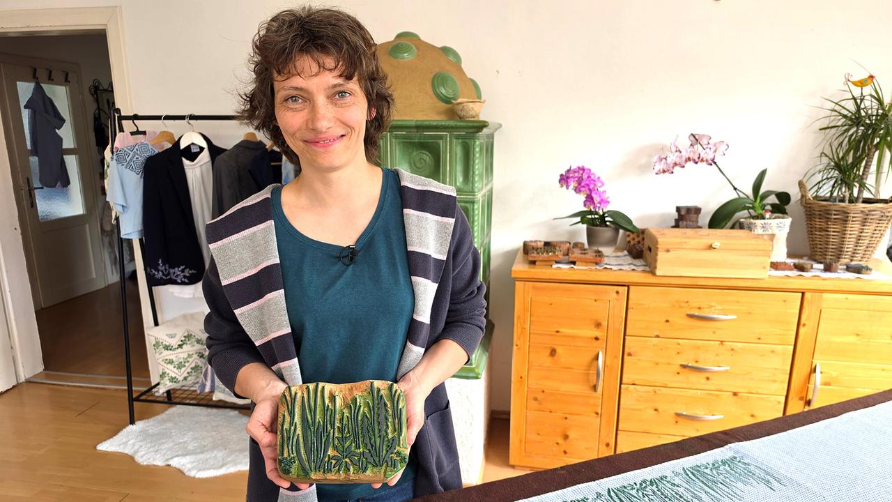 Andrea Maria Breitenbaumer hält eine grün eingefärbte Wiesen-Model in der Hand.