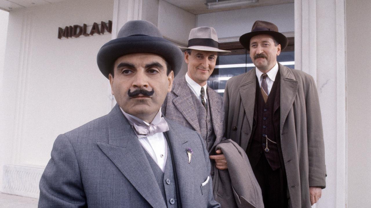 Hercules Poirot schaut nachdenklich in die Ferne während Captain Haistings und Chief-Inspector Japp lächeld auf ihn schauen. 