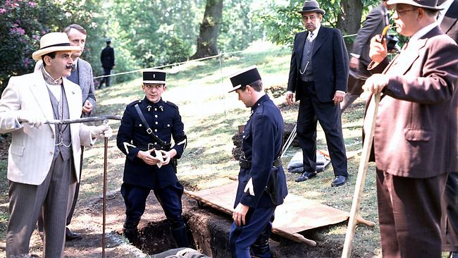 David Suchet (Hercules Poirot), Hugh Fraser (Hastings) und weitere Männer stehen um ein offenes Grab, in dem zwei uniformierte Polizisten stehen.