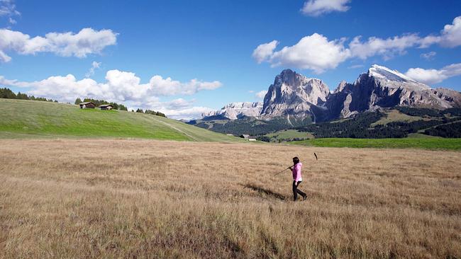 Bergbäuerinnen in Südtirol: Barbara Kastlunger unterwegs auf Seiser Alm - eine Berglandschaft mit Almwiesen und einigen Hütten 