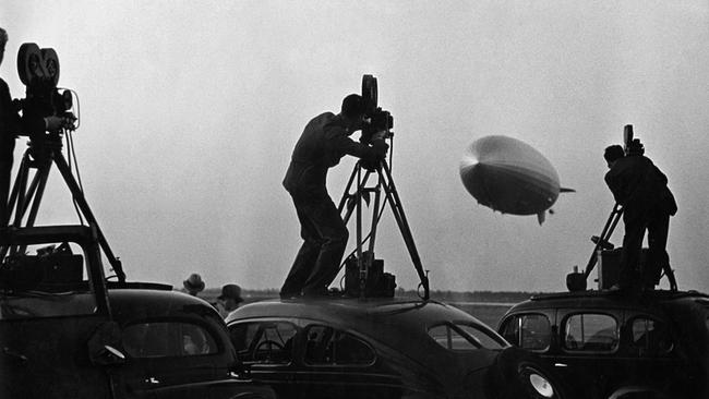 Kameraleute stehen auf Autodächern und filmen die Rückkehr der "Hindenburg" nach ihrer Nordatlantik-Fahrt, 01.01.1936.