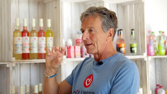 Fruchtsaftproduzent Gerhard Höllinger im Gespräch vor weiße Holzregalen mit verschiedenen Fruchtsaftflaschen