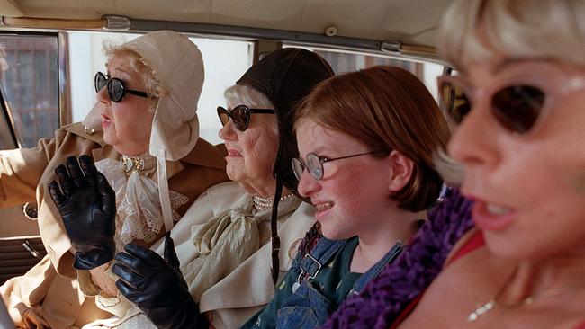 © ORF/Wega Film/Petro Domenigg Gusti Wolf, Jane Tilden, Sarah Veit und Dolores Schmidinger sitzen mit auffälligen Brillen und Kopfbedeckungen dicht nebeneinander in einem Auto.