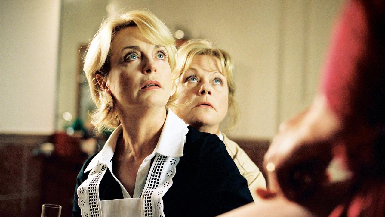 Gisela Schneeberger in Dienstkleidung und Marianne Mendt hinter ihr blicken auf eine ine weitere Person, die im Vordergrund mit ausgestrecktem Arm im Bild erscheint.