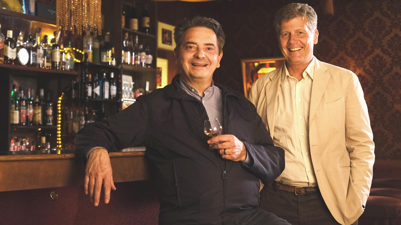 Christoph Wagner-Trenkwitz und Karl Hohenlohe stehen nebeneinander an einer Bar. Wagner-Trenkwitz hat ein Glas in der Hand. Beide lächeln.
