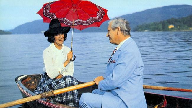 (v.li.): Rudi Carrell und Gunther Philipp sitzen in einem Ruderboot auf dem Wörthersee. Rudi Carrell ist als Frau verkleidet und hält einen roten Regenschirm aufgespannt in der Hand.