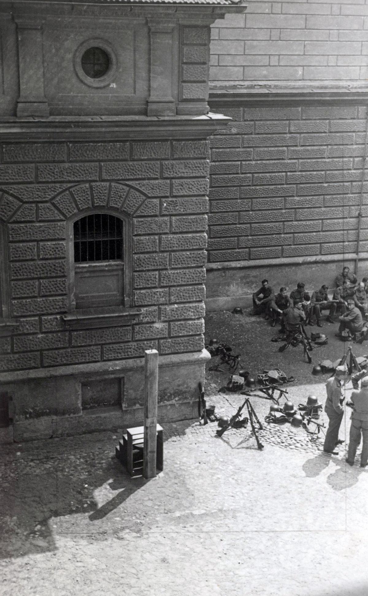 Galgen in einem Gefängnishof, vermutlich in Graz, mit lagernden Heimwehrangehörigen