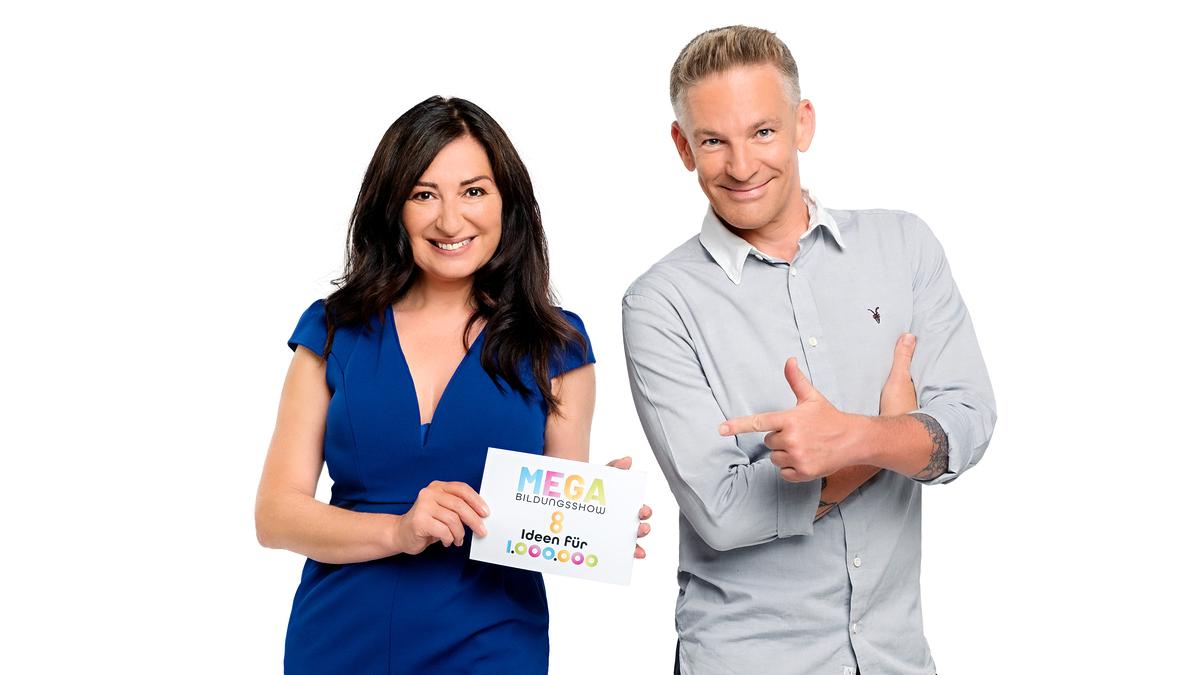 © ORF Hans Leitner Die Moderatoren Ani Gülgün-Mayr und Andi Knoll stehen nebeneinander und lächeln.