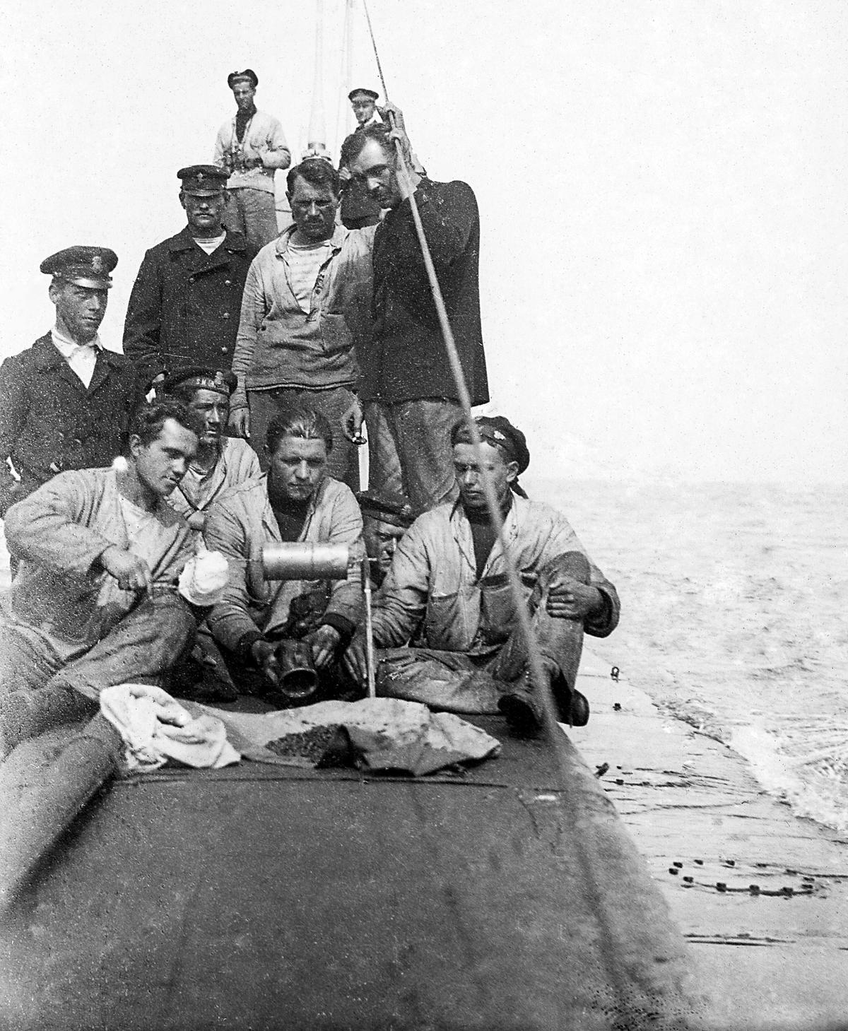 Im Bild: Die Männer des U-Boots U4 sitzen auf dem U-Boot und kochen mit der Lötlampe.
