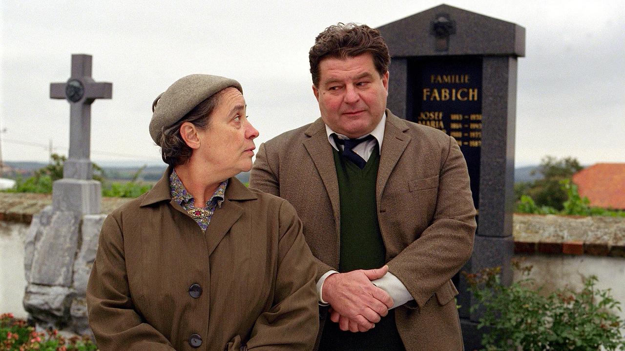 Aloisia Habesam und Simon Polt stehen nebeneinander auf einem Friedhof und sehen einander fragend an.