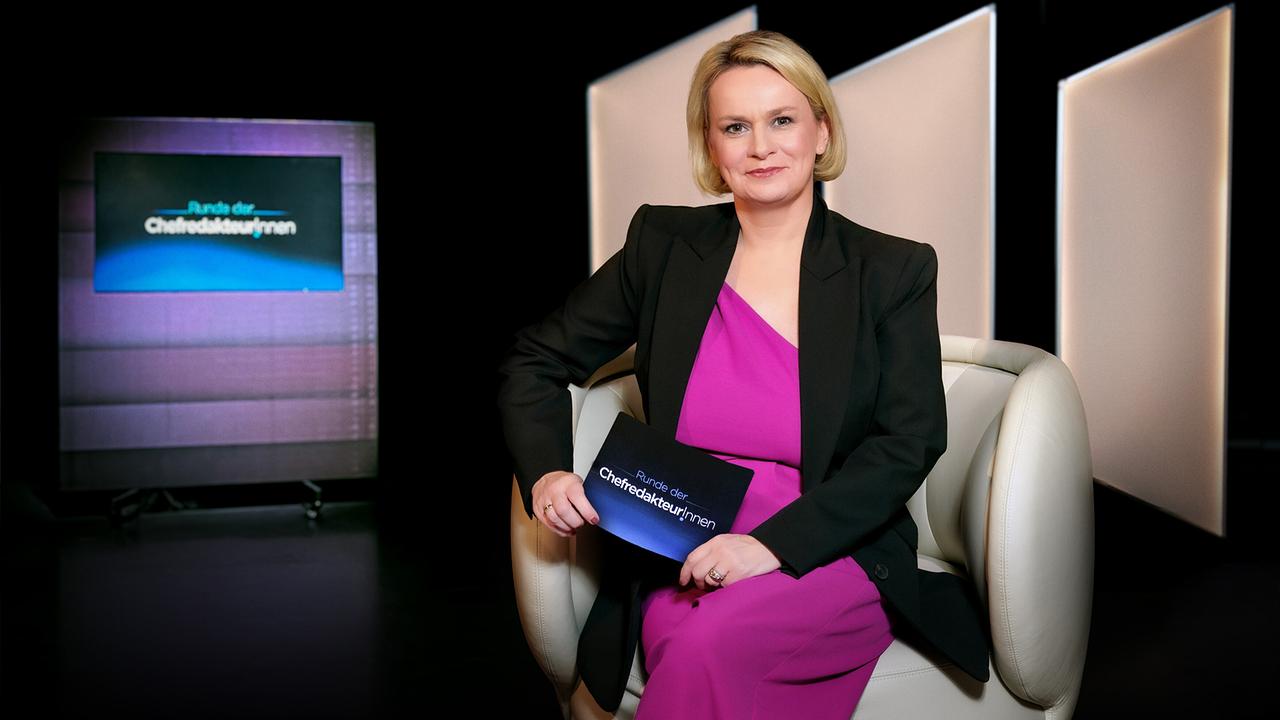 Lou Lorenz-Dittlbacher sitzt in einem weißen Polstersessel im "Runde der ChefredakteurInnen"-Studio