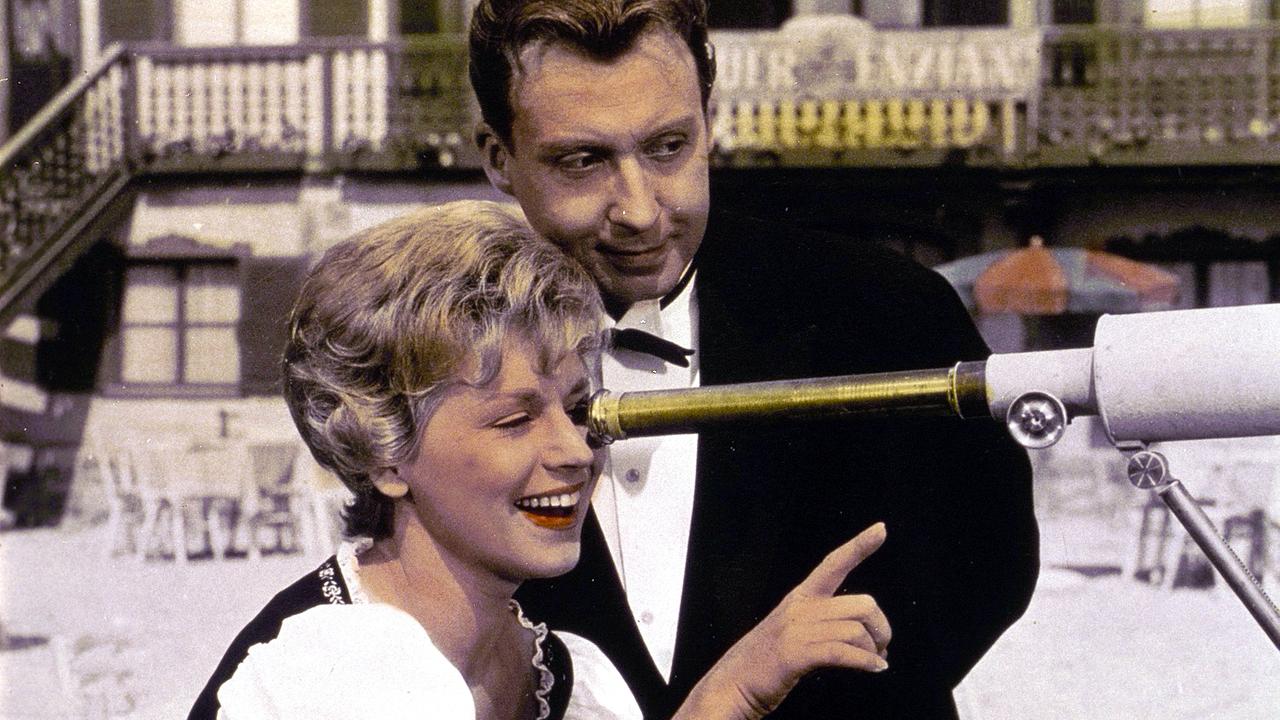 Saison in Salzburg (Komödie 1961) Im Bild: Waltraut Haas (im Profil) sieht durch ein Teleskop, neben ihr steht Peter Alexander freundlich lächelnd.